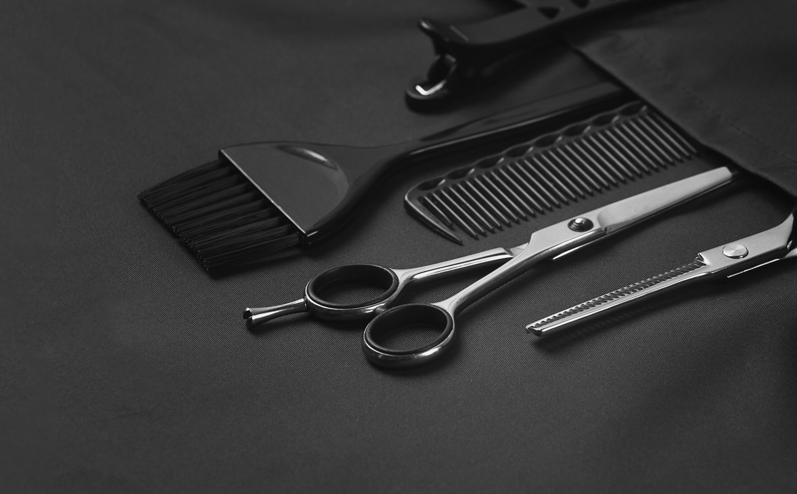 Professional barber tools, in the pocket, black stylist apron, horizontal, no people,